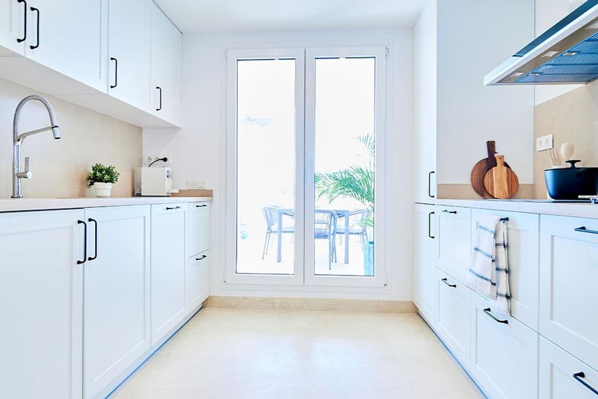 Moderne keuken met strakke kasten en een groot raam dat helder natuurlijk licht biedt in Marbella.
