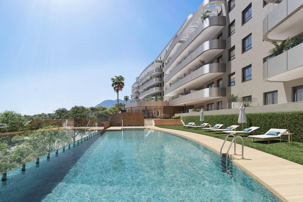Groot zwembad omringd door ligbedden in een hedendaags appartementencomplex in Torremolinos.