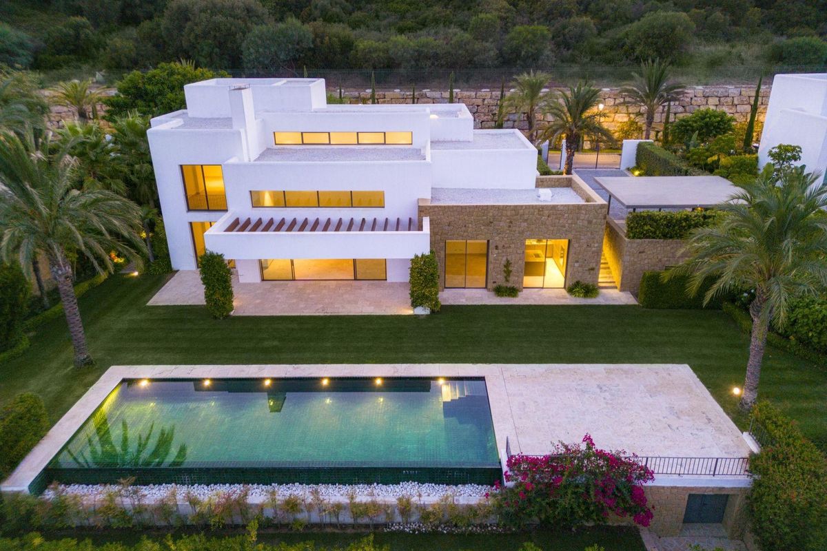 Luchtfoto van een moderne 5-slaapkamer villa in Casares, met een zwembad en weelderige tuinen onder een heldere lucht.