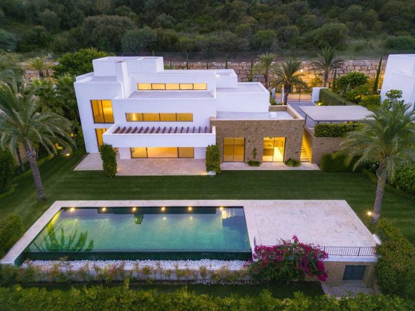 Luchtfoto van een moderne 5-slaapkamer villa in Casares, met een zwembad en weelderige tuinen onder een heldere lucht.
