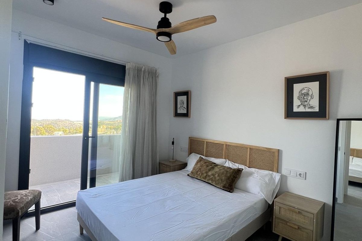 Uitnodigende slaapkamer met een balkonzicht en elegante meubels in een 3-slaapkamer townhouse in Polop, Spanje.