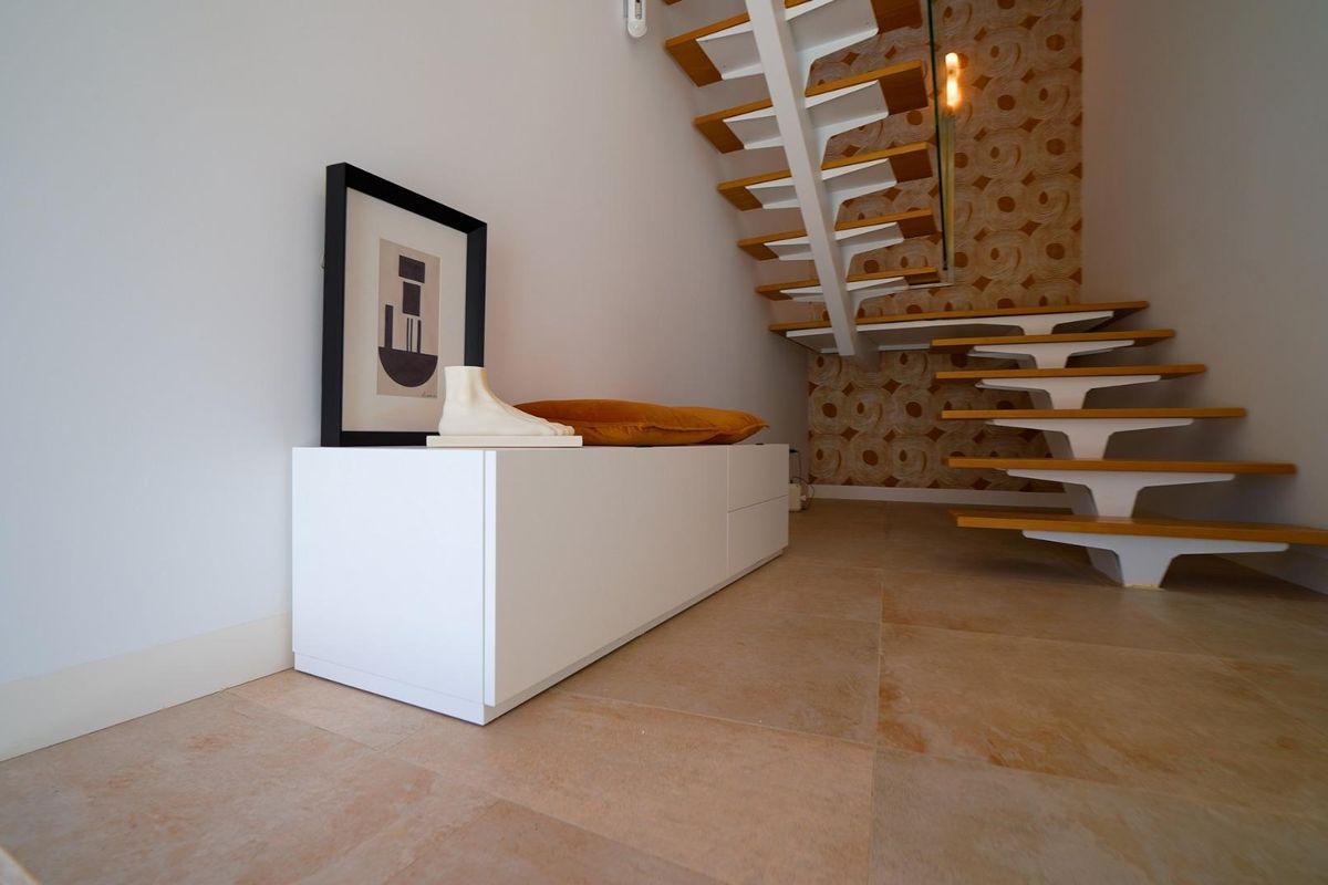 Heldere entree van de villa in Orihuela Costa met een uniek trapontwerp en stijlvolle decoratie.