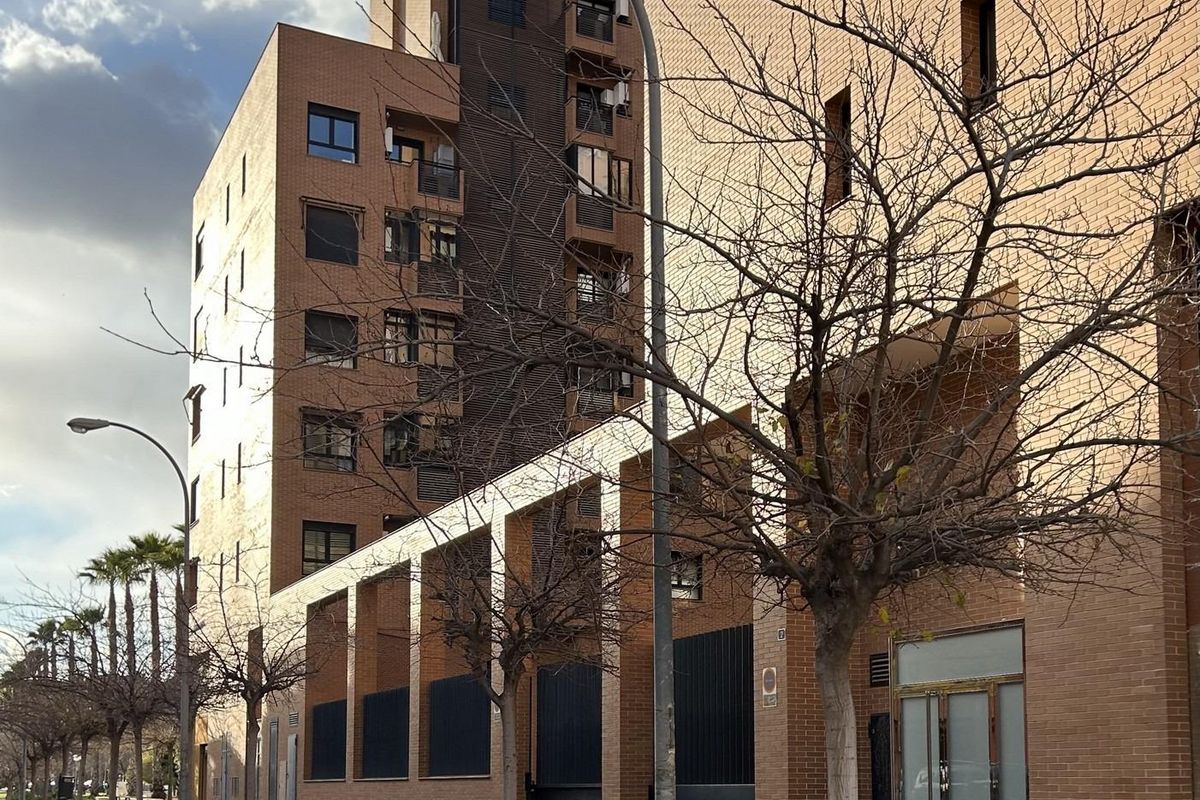 Gevel van het moderne appartementencomplex met bomen langs de straat, gelegen in het stedelijke Alicante.