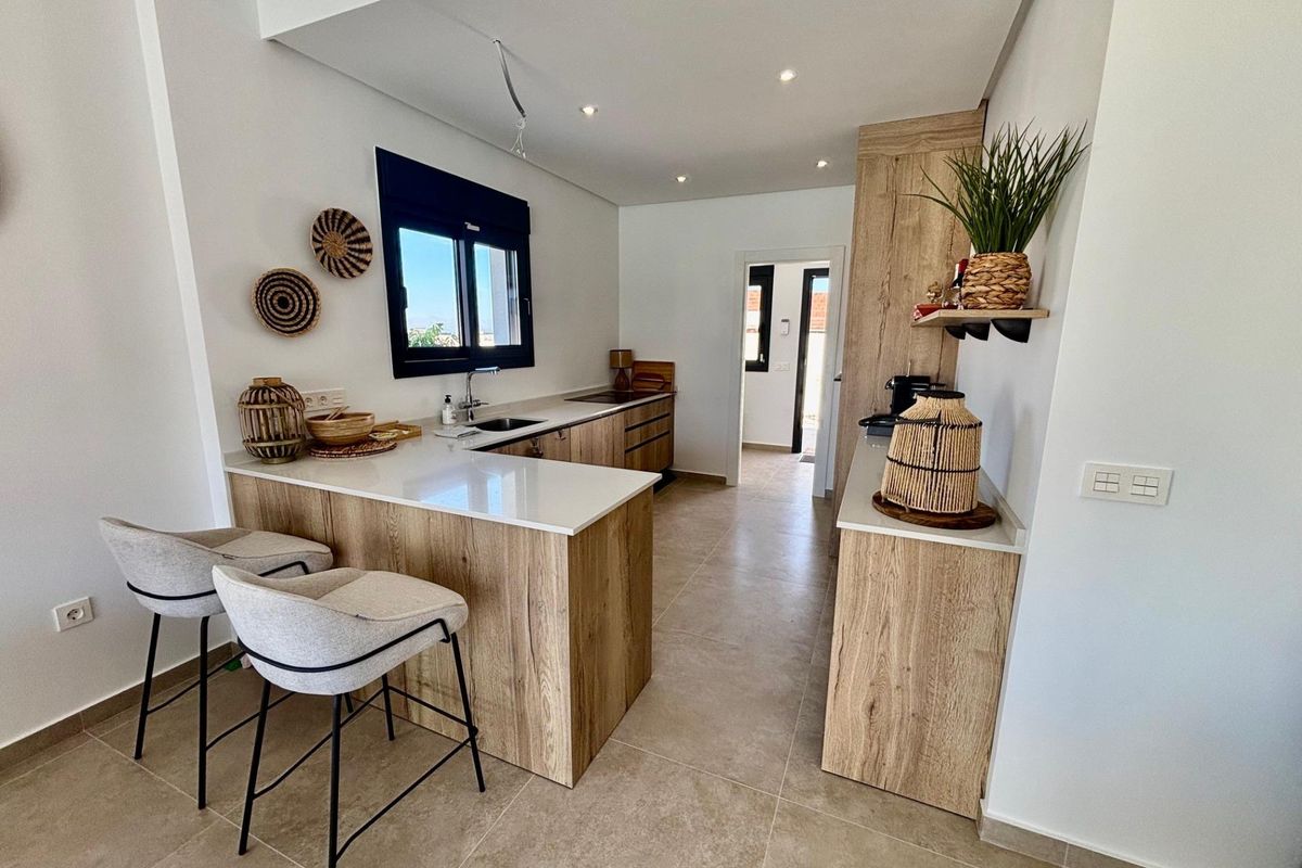 Moderne keuken in een villa in Rojales, met stijlvolle houten kasten en een ontbijtbar voor casual dineren.