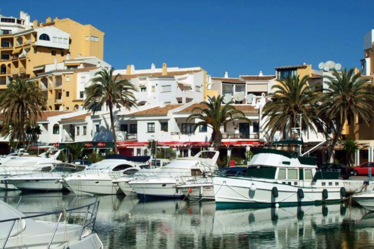 Charmante marina in Marbella met boten aan de kade naast kleurrijke gebouwen en palmbomen.