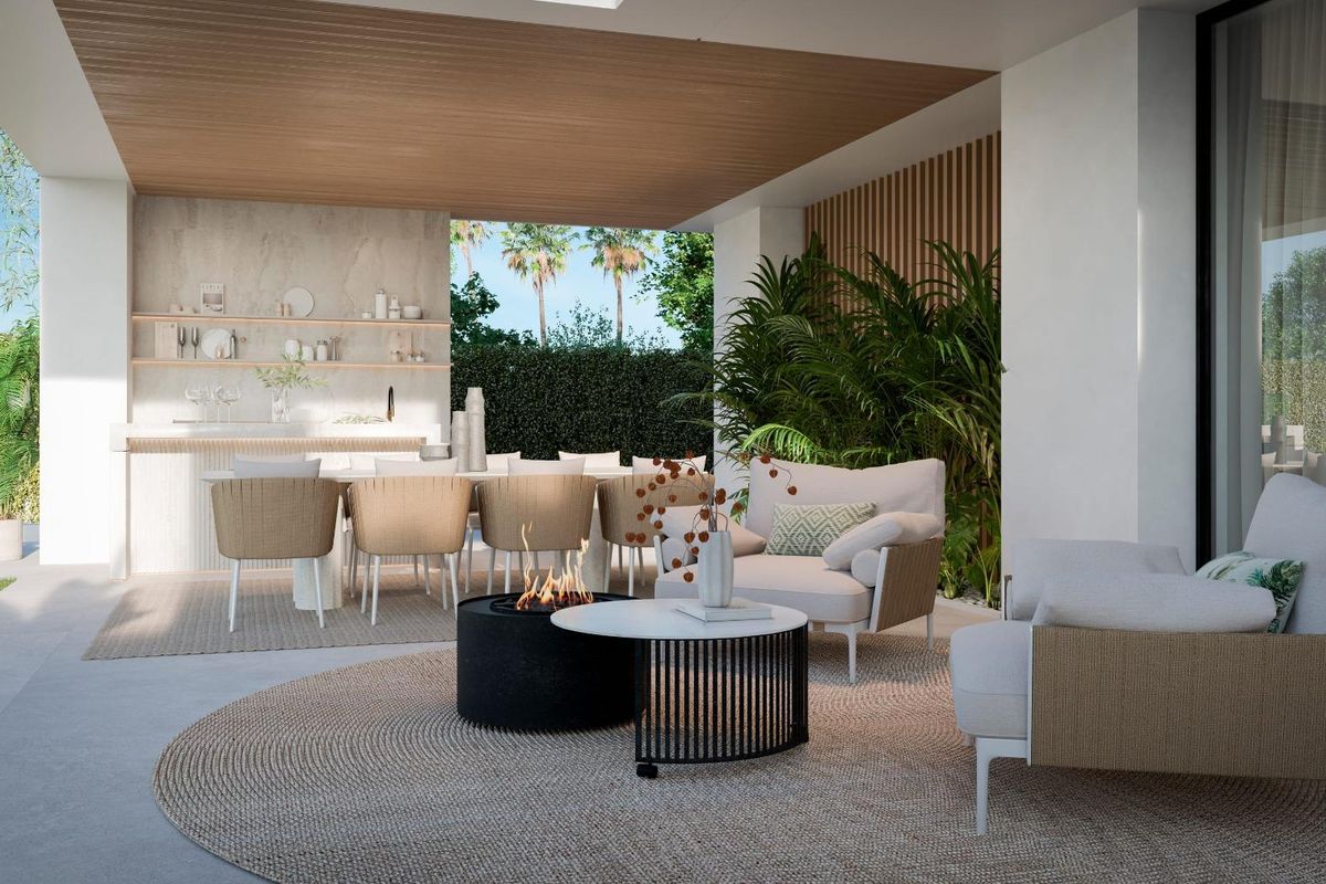 Eethoek in de openlucht van een luxe villa in Estepona, met een vuurplaats, tuinmeubelen en een kookgedeelte.