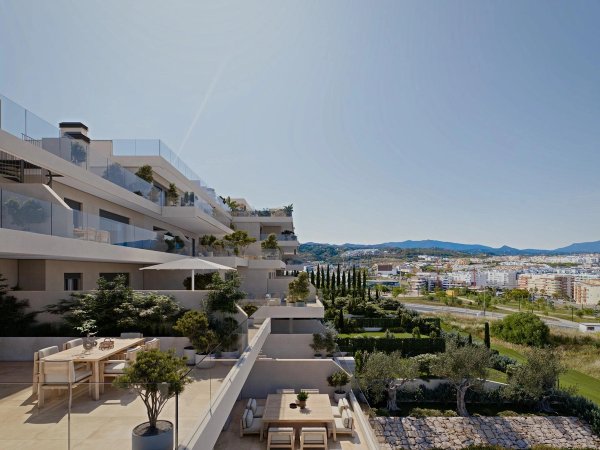 Modern terras van appartement in Estepona met uitzicht op een groene tuin en zitgedeelte.