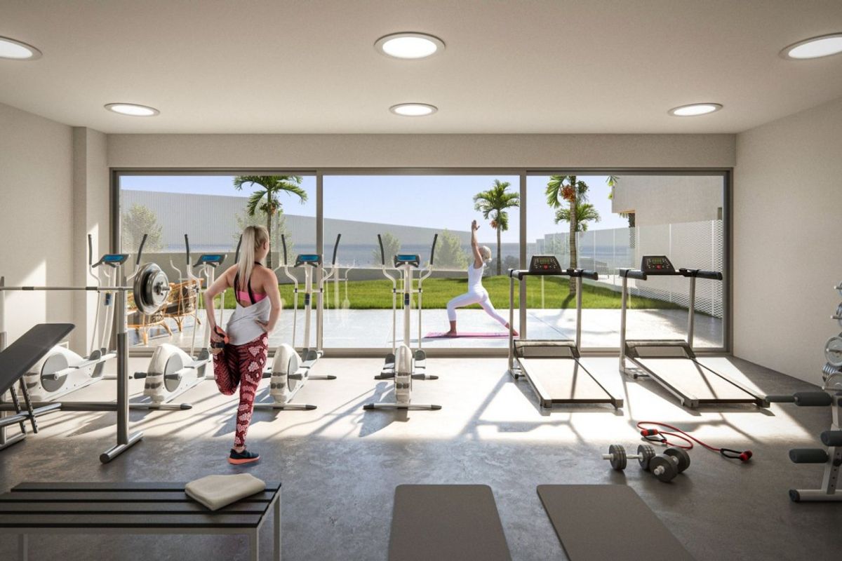 Goed uitgeruste gym met fitnessapparatuur en uitzicht op het landschap in appartementencomplex in Estepona.