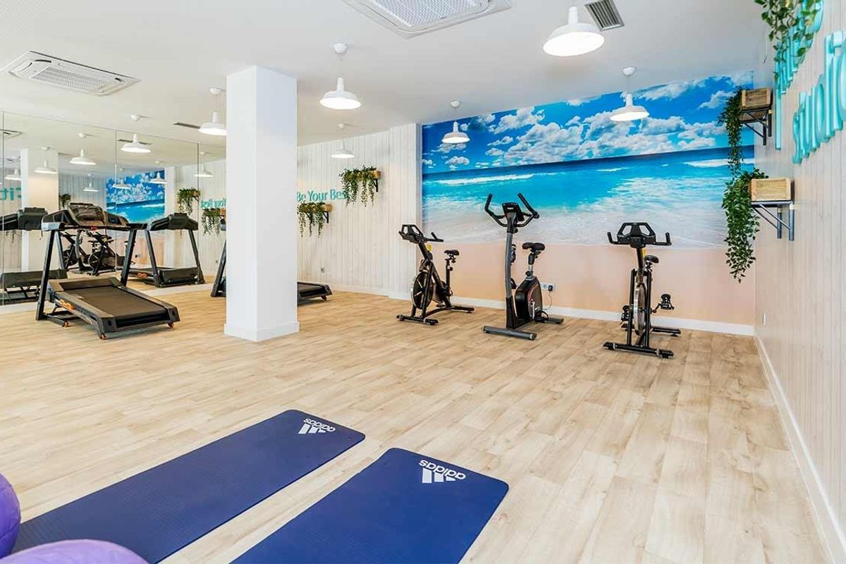Moderne fitnessruimte in Benalmádena, uitgerust met oefenmachines en yogamatten, die een uitnodigende sfeer creëert.