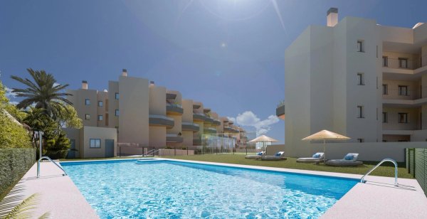 Zwemgebied met ligbedden en parasols, omringd door appartementen in Torrox, Costa del Sol, Spanje.