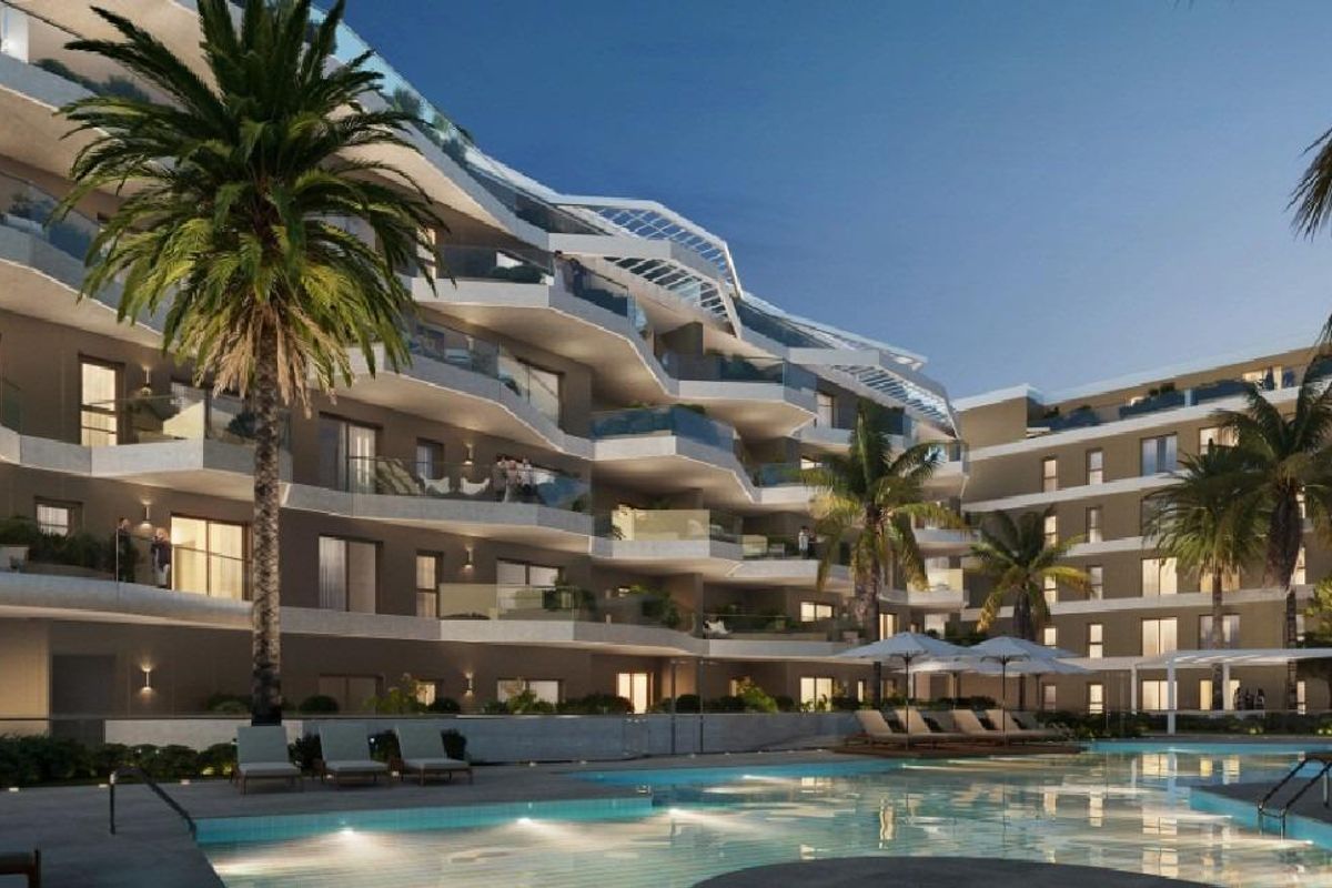 Avondzicht op het appartementencomplex met een zwembad en palmbomen, die een ontspannen kustsfeer in Mijas uitstralen.