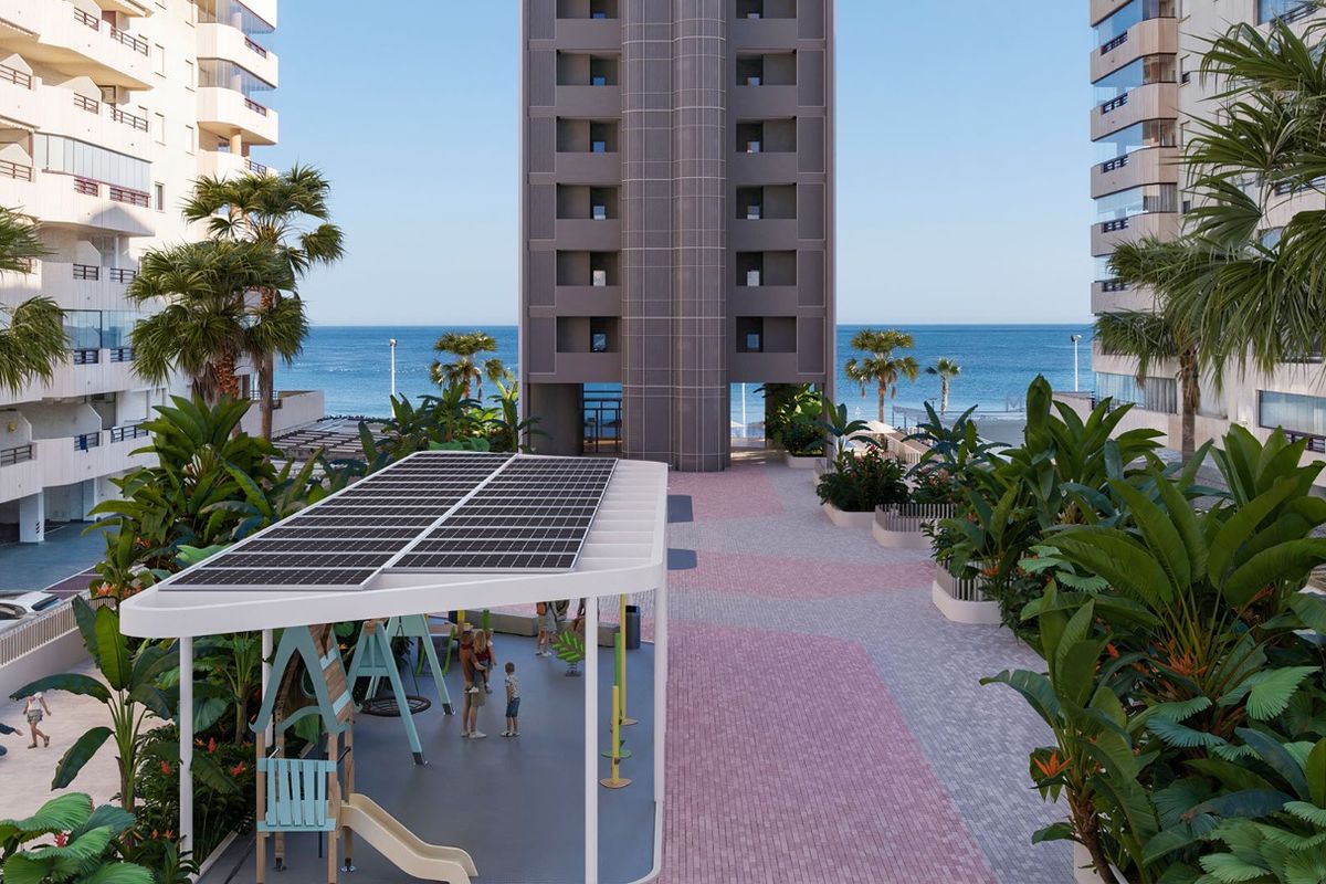 Entree van het appartementencomplex met palmbomen en zonnige paden, met uitzicht op zee in Calpe.