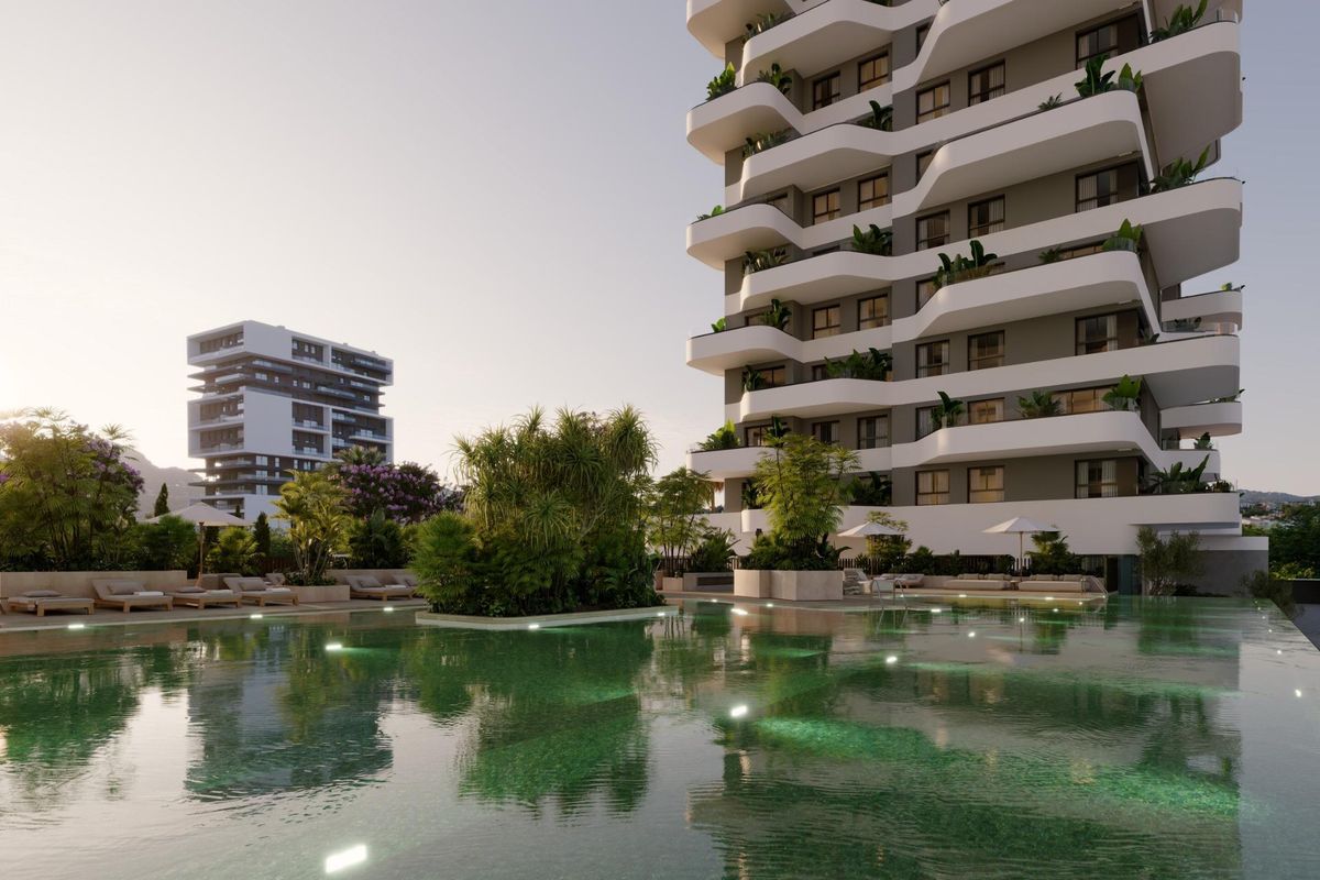 The exterior of a modern apartment building with a large pool and greenery, located in Calpe, Costa Blanca.