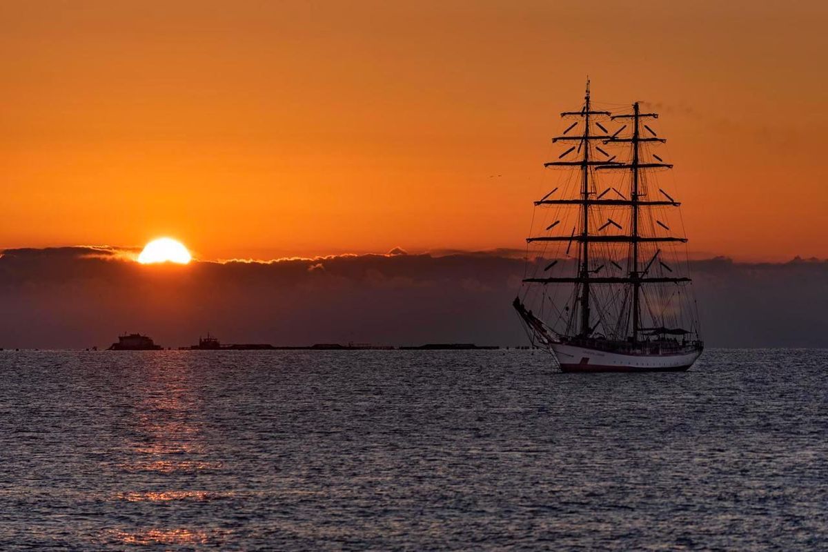 Prachtig zonsondergang uitzicht over het water, met een tall ship op de voorgrond in Villajoyosa, Spanje.