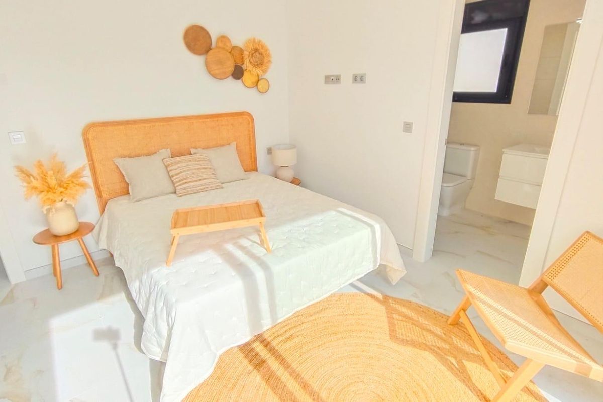 Heldere gastenslaapkamer met een ruime bed en stijlvolle decoratie in een villa in Pilar de La Horadada.