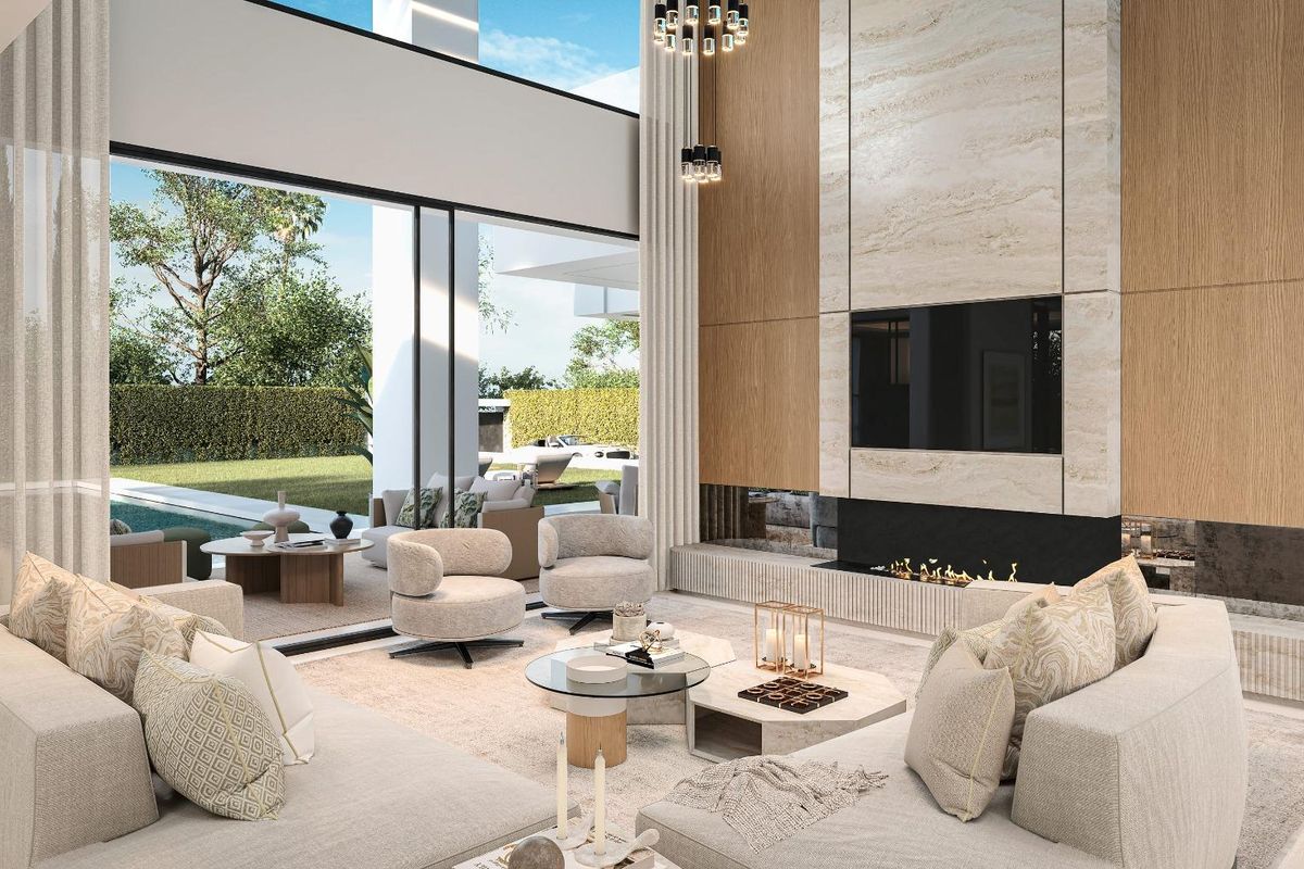Woonkamer van een villa in Estepona met hoge plafonds, grote ramen, een open haard en neutraal getinte, moderne meubels.