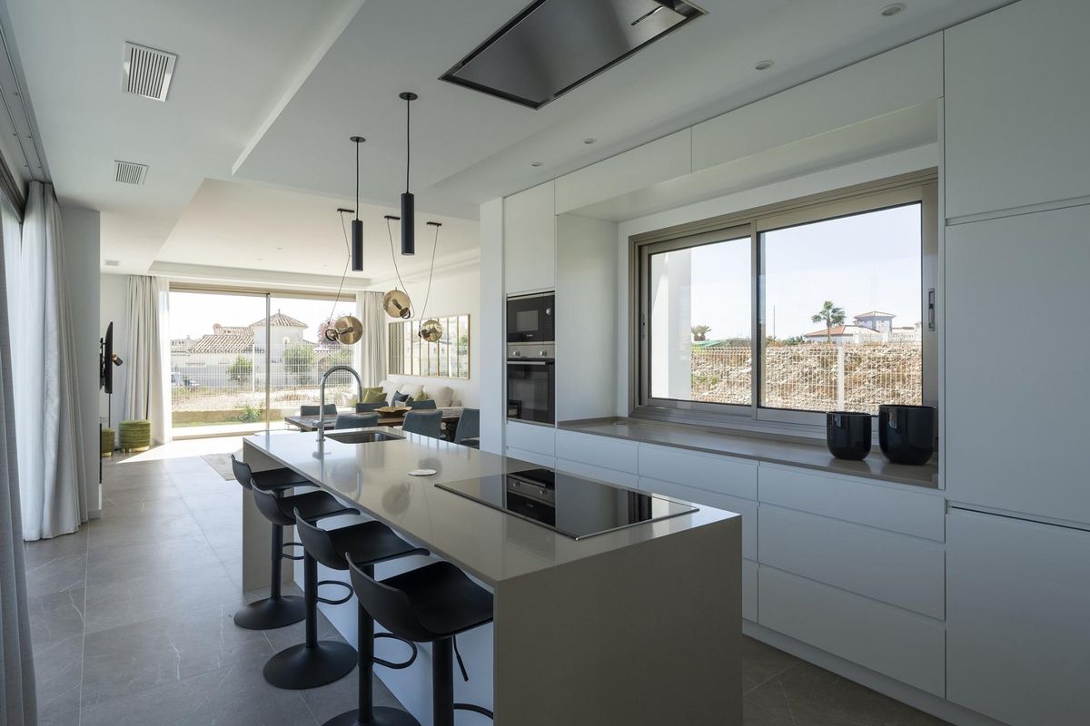 Strakke keuken met eilandzitplaatsen en moderne apparaten in een 4-slaapkamer villa gelegen in Mijas, Costa del Sol.