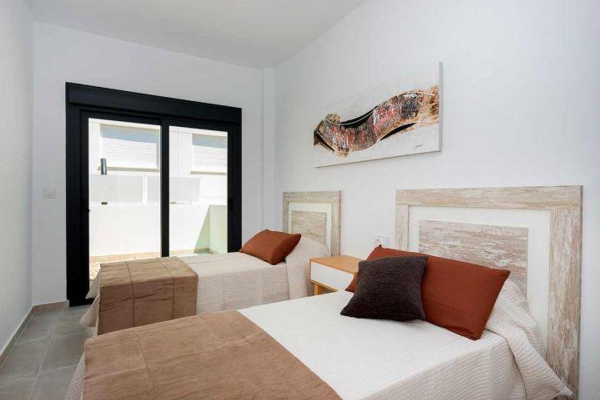 Heldere slaapkamer met twee eenpersoonsbedden in een bungalow in Daya Nueva, ontworpen voor comfort met natuurlijk licht en stijlvolle inrichting.