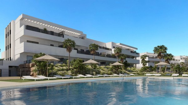 Buitenzicht op een modern appartementencomplex met een zwembad en weelderige tuinen in Estepona.