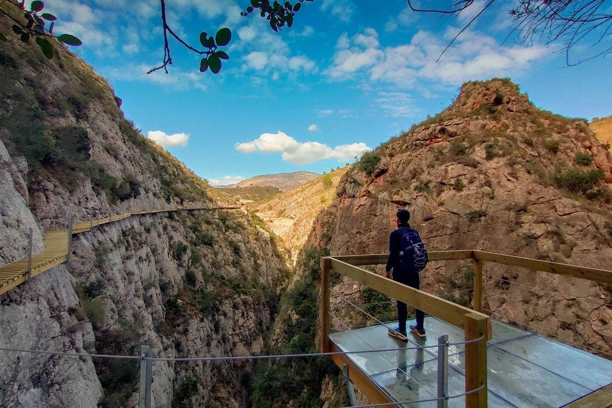 View of a person on a wooden platform in El Caminito del Rey near Relleu, Costa Blanca North, with mountains around.