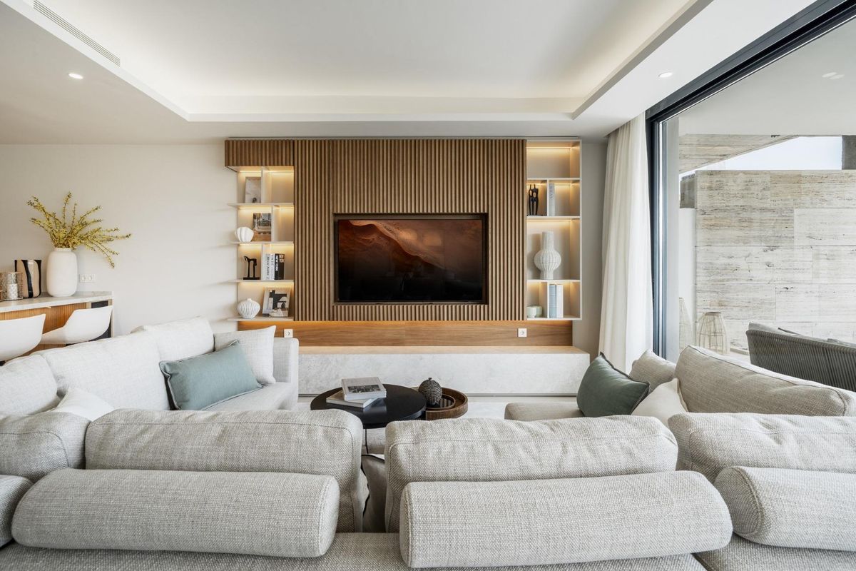Sfeervolle woonkamer in een appartement in Marbella, met een comfortabele bank en moderne tv-display.