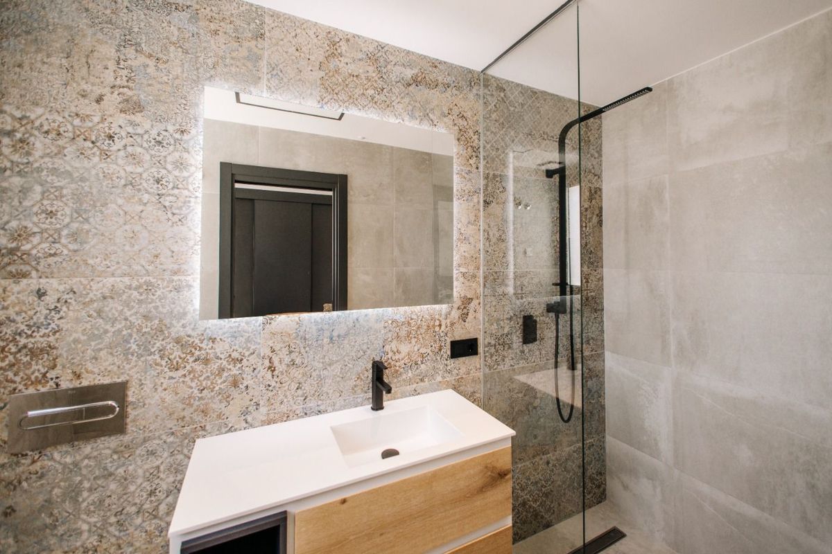 Modern badkamer met ingewikkeld tegelontwerp, grote spiegel en inloopdouche in Rojales, Costa Blanca Zuid.