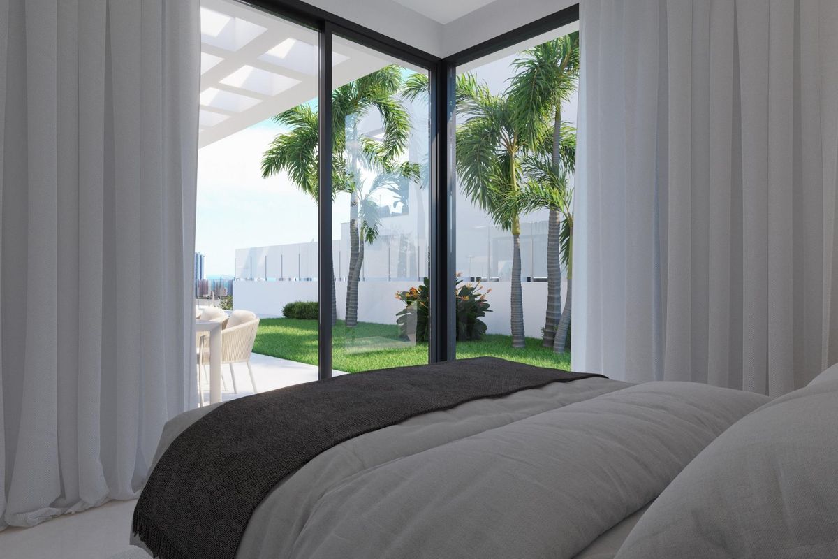 Gezellige slaapkamer met grote ramen die uitkomen op een tuin in een moderne villa in Finestrat, Costa Blanca Noord.