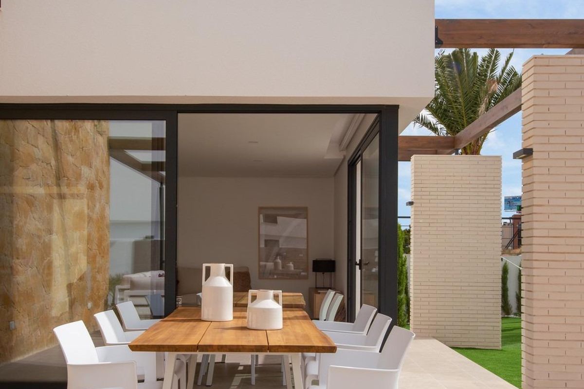 Buiten eetruimte met een houten tafel en witte stoelen bij een moderne villa in Orihuela Costa.