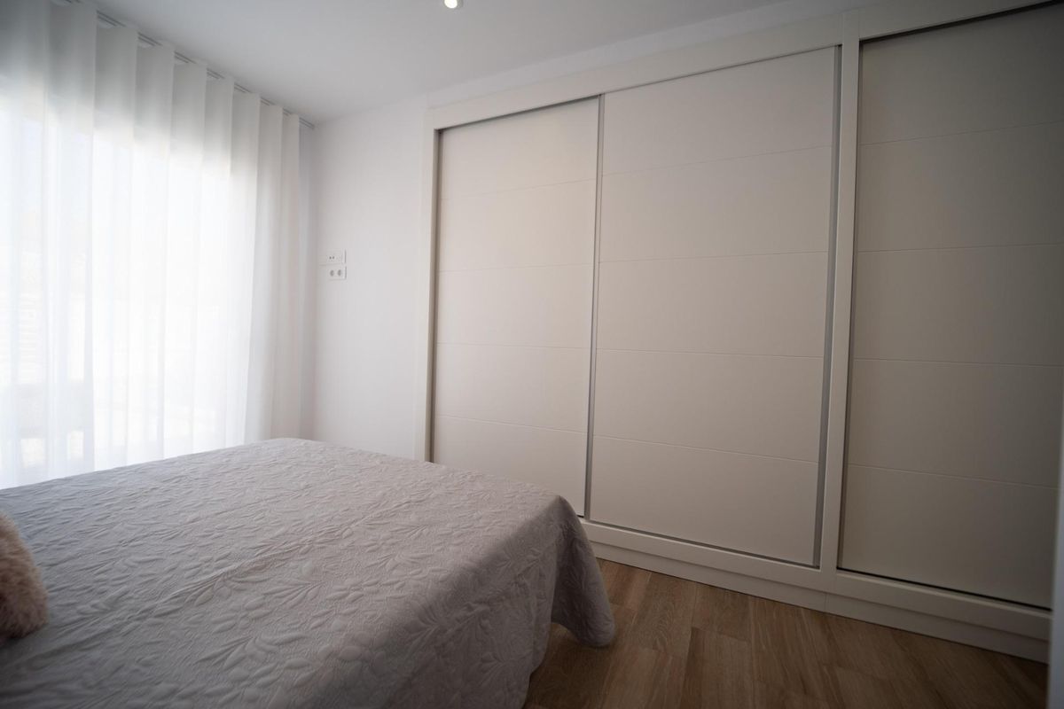 Bedroom interior showing double bed and large built-in wardrobe in a San Javier townhouse. Bright and modern.