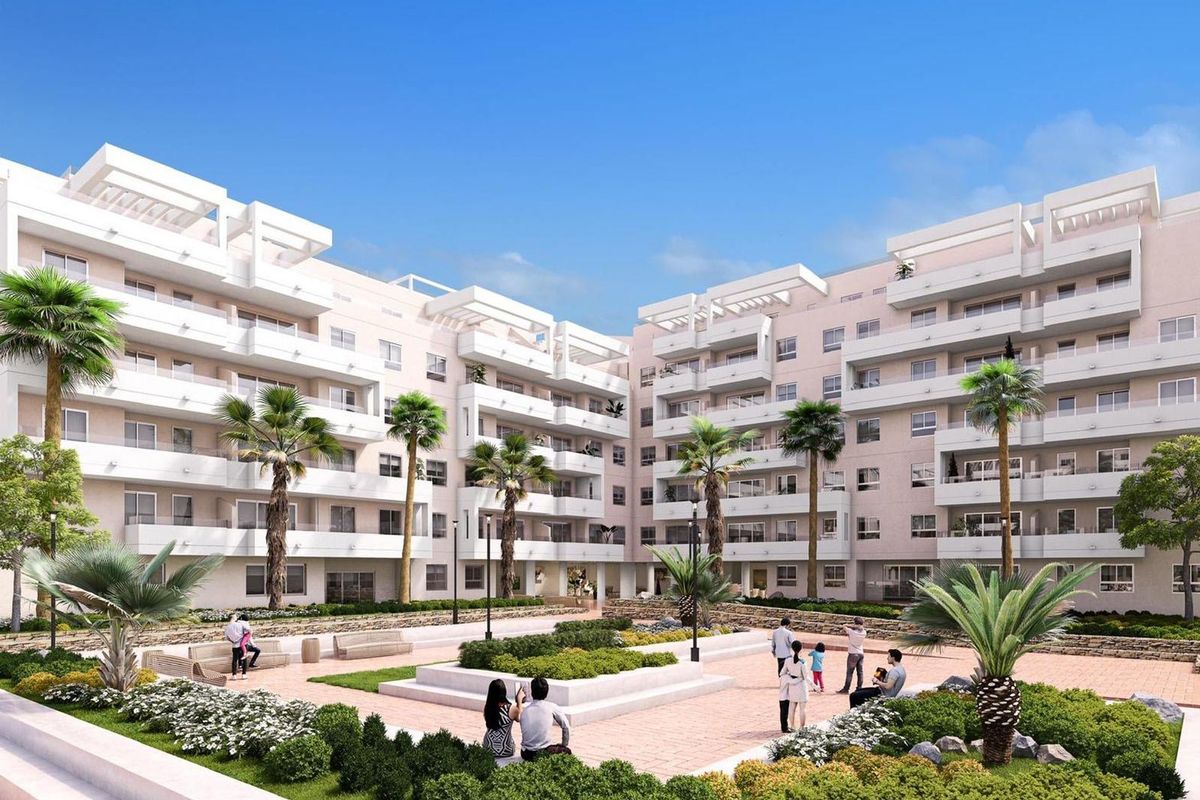 Buitenzicht op een modern appartementencomplex in Marbella met aangelegde tuinen en palmbomen.