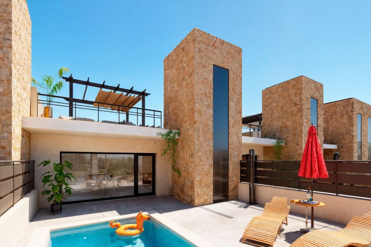 Buitenzicht op een moderne townhouse met zwembad in Fuente Álamo, Costa Calida, met terrassen en stenen muren.