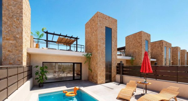 Buitenzicht op een moderne townhouse met zwembad in Fuente Álamo, Costa Calida, met terrassen en stenen muren.