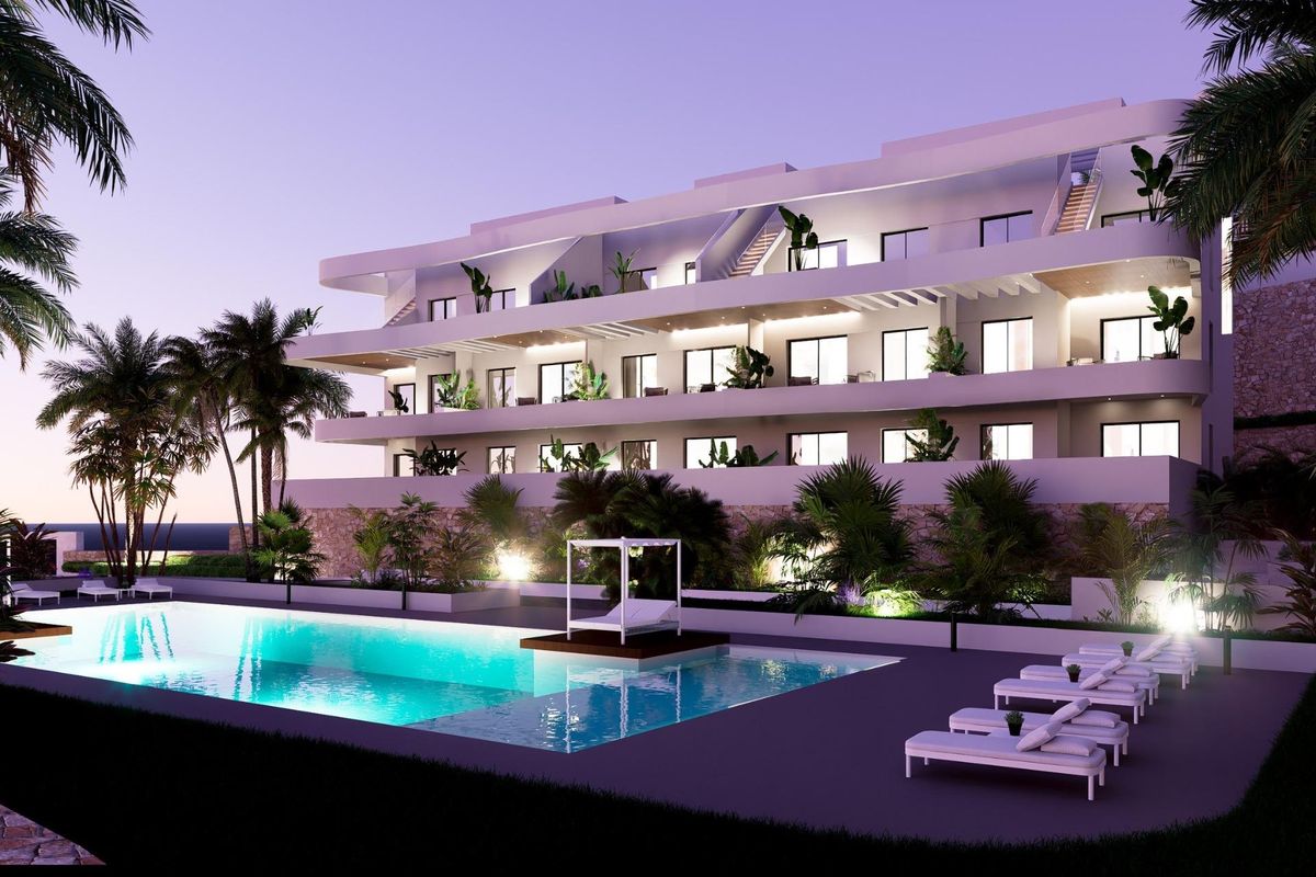 Modern penthouse gebouw met palmbomen en zwembad bij het vallen van de avond in Finestrat, Costa Blanca Noord.