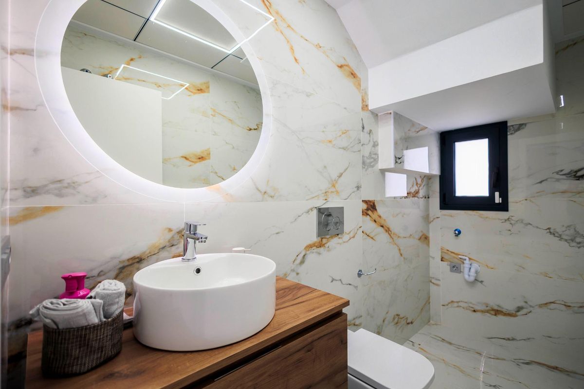 Elegante badkamer met ronde spiegel in een 3-slaapkamer villa in Pilar de La Horadada, met luxe marmeren afwerkingen.