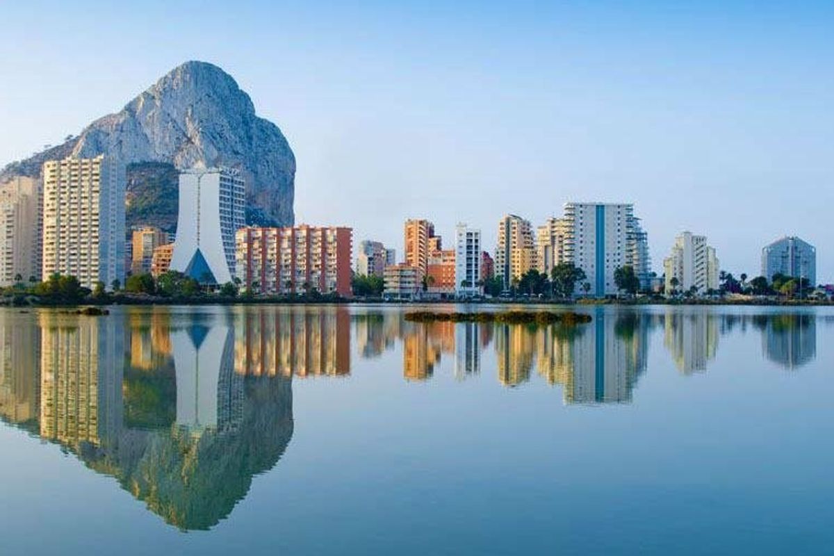 Pittoresk uitzicht aan het meer in Calpe met de opvallende rots en stadsreflecties in het water.
