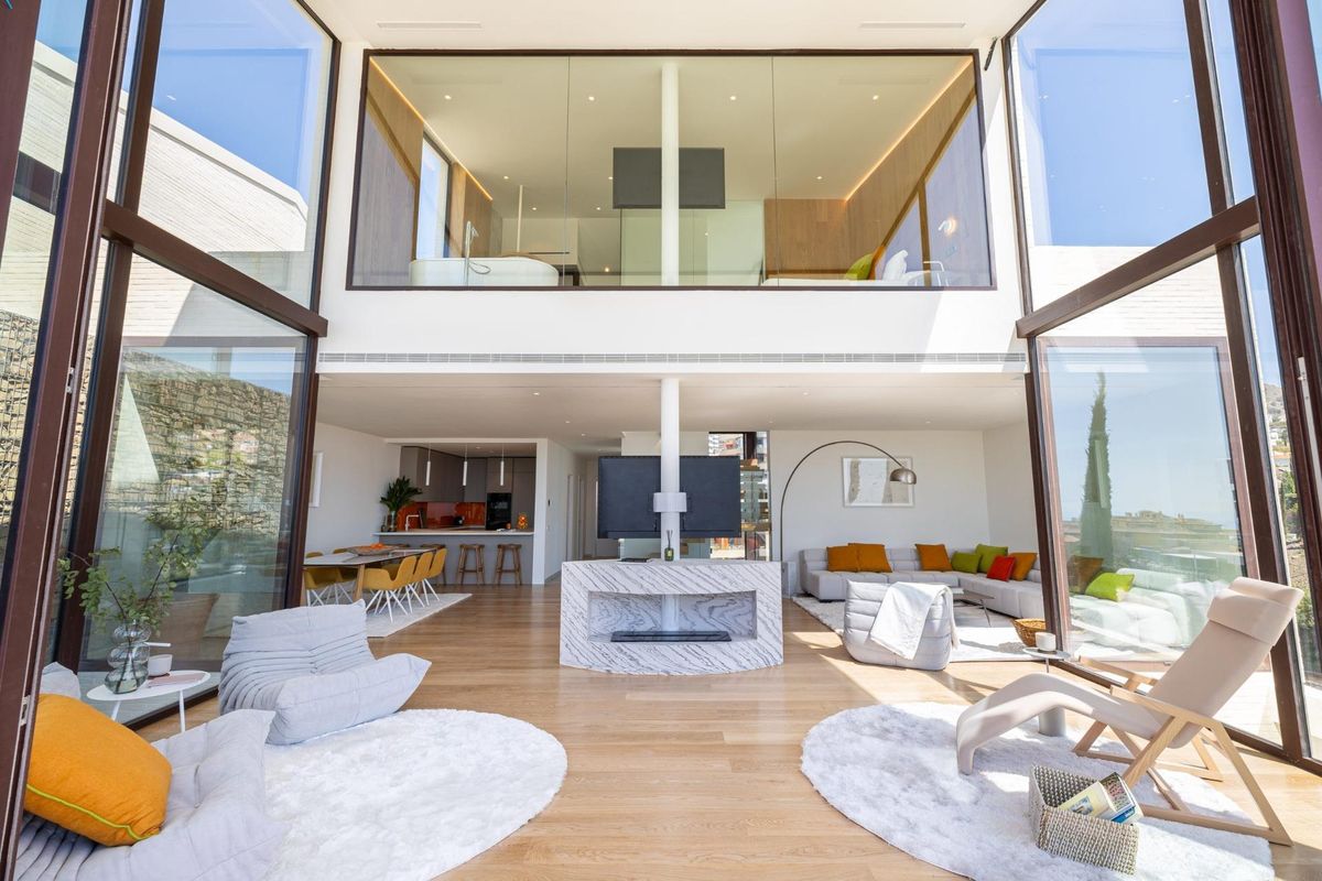 Open woonkamer in een 4-slaapkamer herenhuis in fuengirola met grote ramen, die leiden naar de keuken, eetkamer en terras.