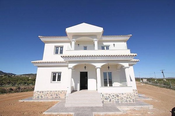 Buitenkant van een moderne villa met 4 slaapkamers in Pinoso, Spanje, met een schone gevel en open ingang.