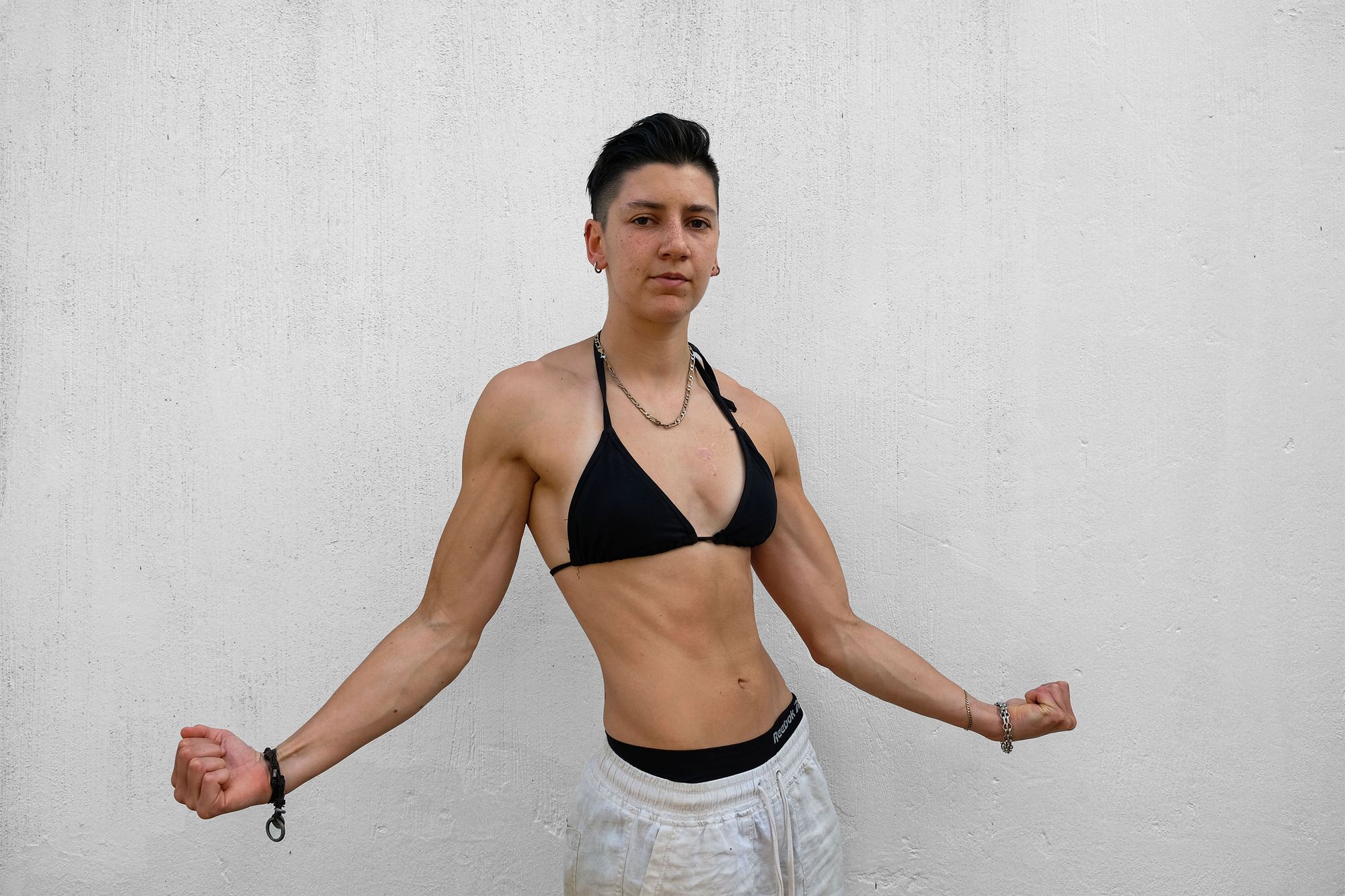 Athlete standing with arms out and fists clenched against a white wall