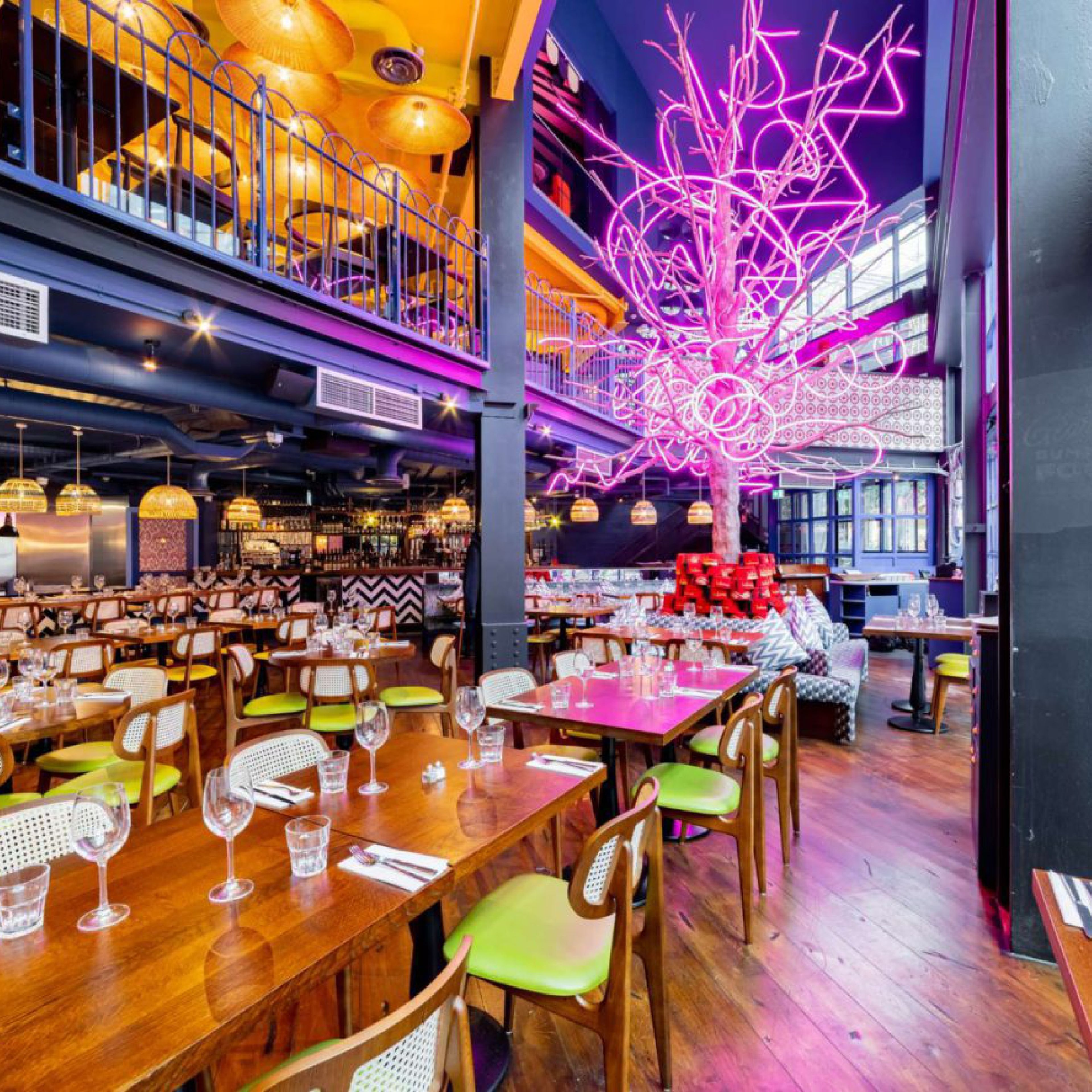 Lokma Westfield restaurant interior with wooden tables, lime-green chairs and a pink neon tree sculpture