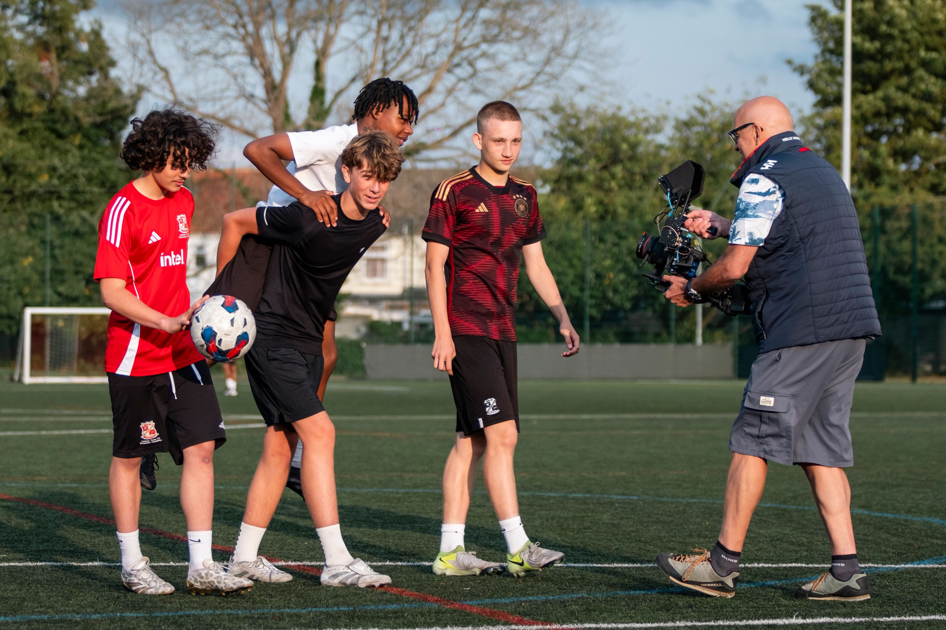 Camera operator filming teenage footballers on an astroturf pitch for the BeU Swindon campaign shoot