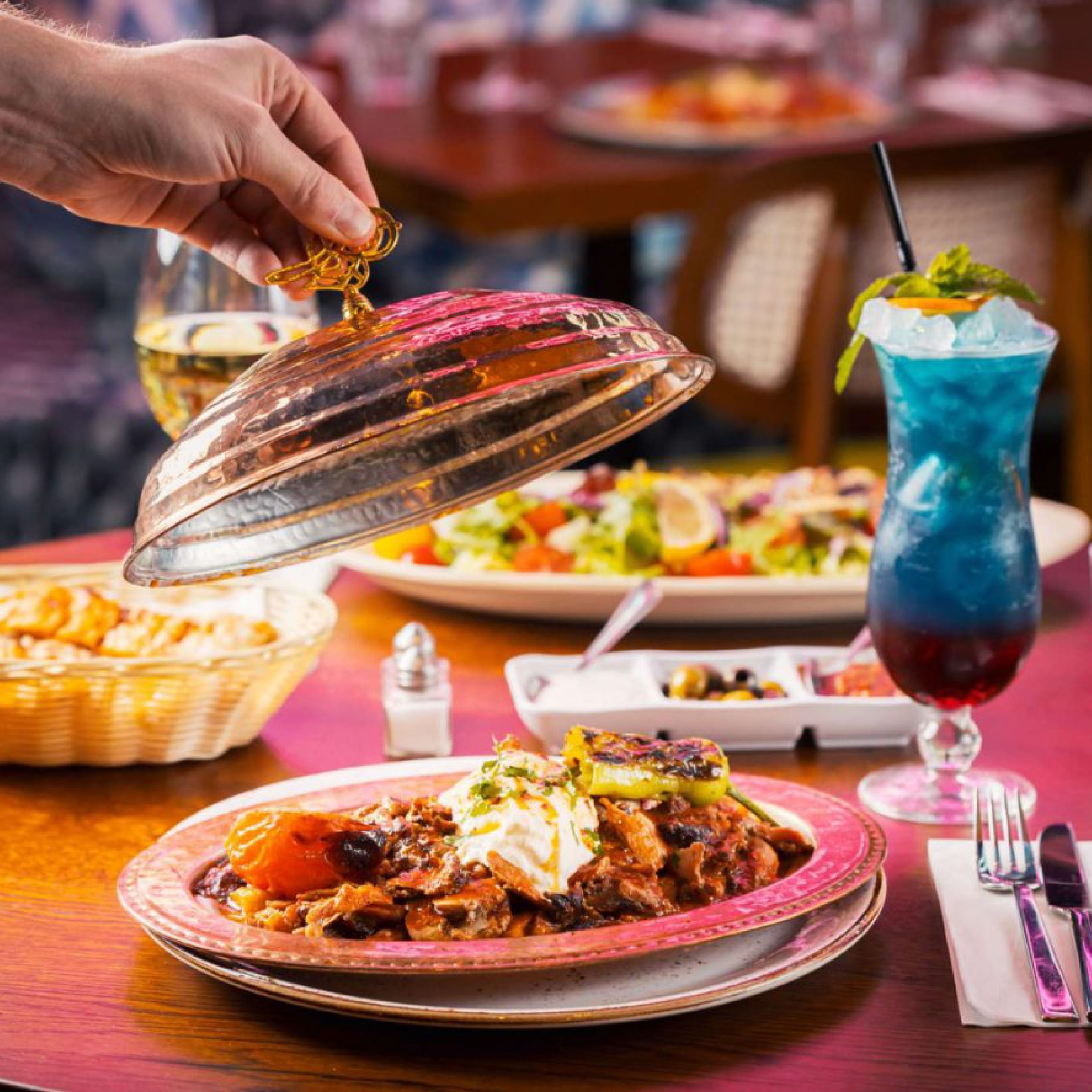 Turkish dishes at Lokma Westfield as a copper cloche is lifted over a mezze plate beside a blue cocktail