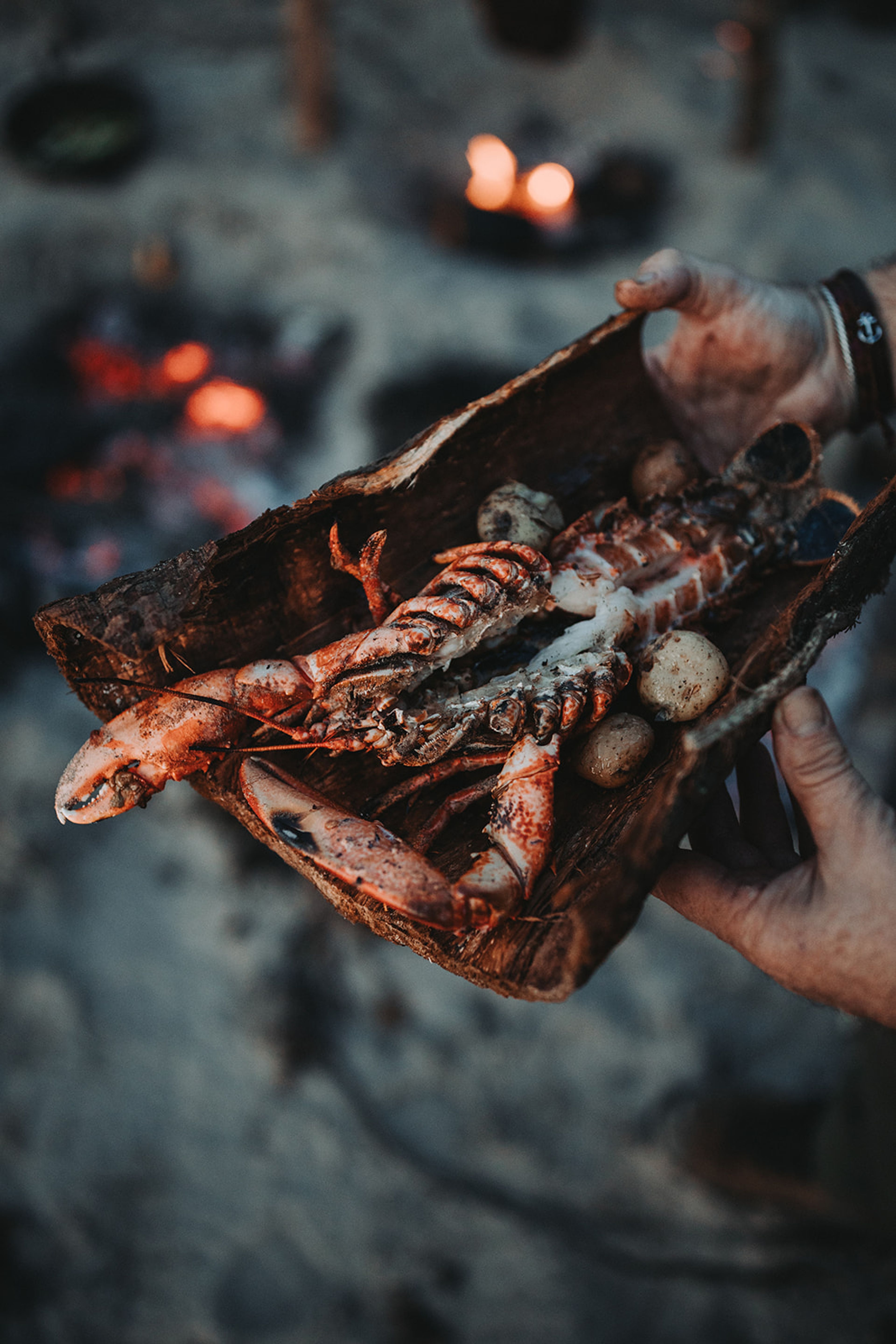Fire-cooked langoustines and potatoes served on bark beside the embers for The Kirkmichael Arms