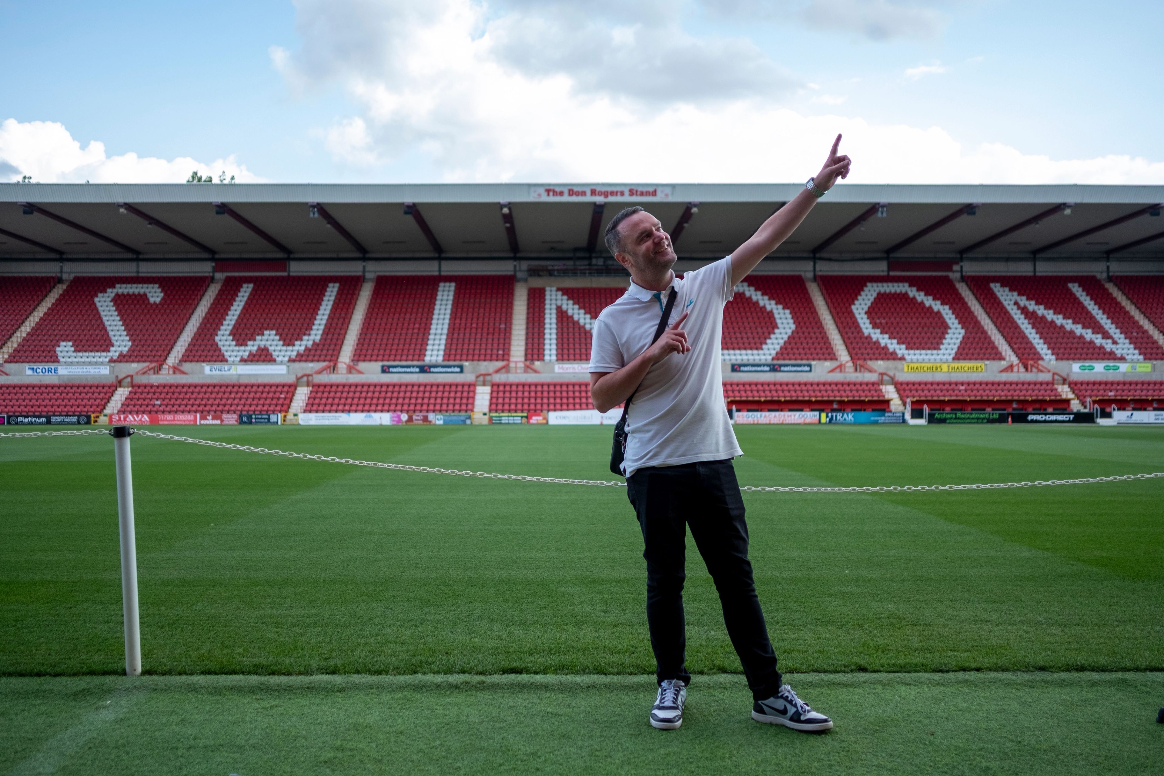 Presenter pointing to the SWINDON lettering across the stadium stands during the BeU Swindon shoot
