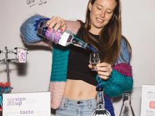 Robyn Smith of rum et al. pouring a measure into a tasting glass beside a whiteboard asking “Which rum did you prefer?”