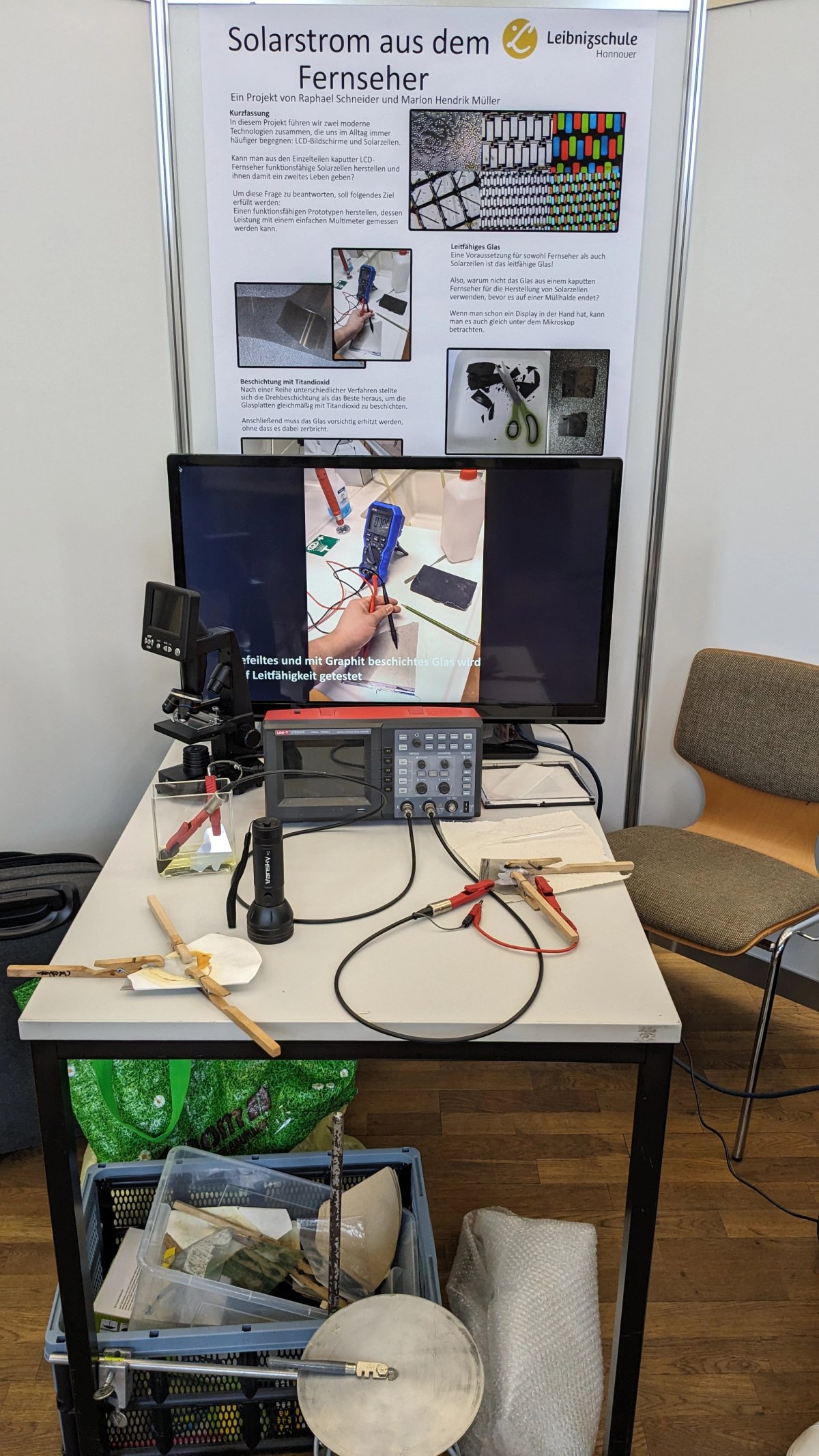 A desk loaded with sciency stuff (different Prototypes, Oszilloskope, Mikroskope and a Screen)