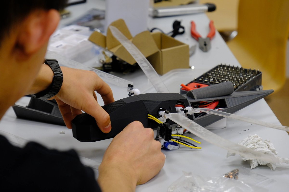 A behind the shoulder shoot looking at a prototype, that is dragonfly like in appearance with transparent wings. 