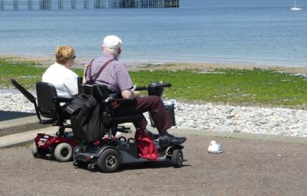 Two people in wheelchairs looking at a lake
