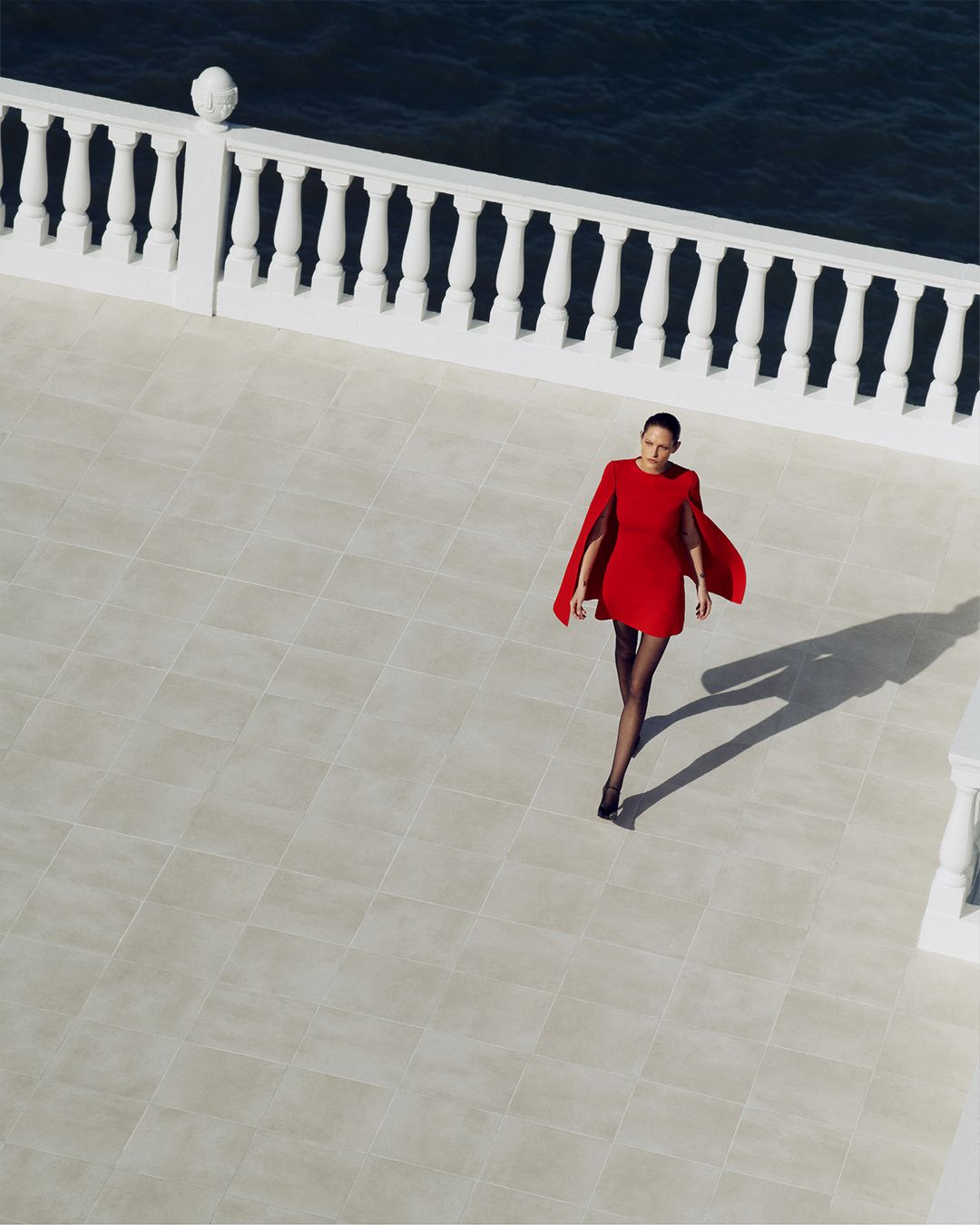 Crepe Knit Red Cape Dress walking on tiled balcony