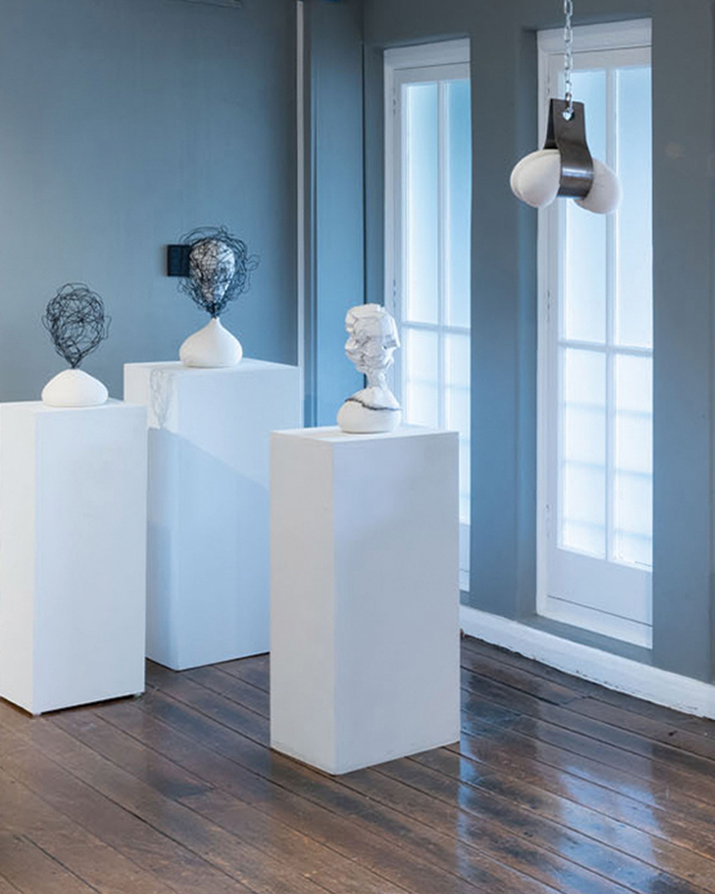 Gallery room featuring three stands with modern sculptures
