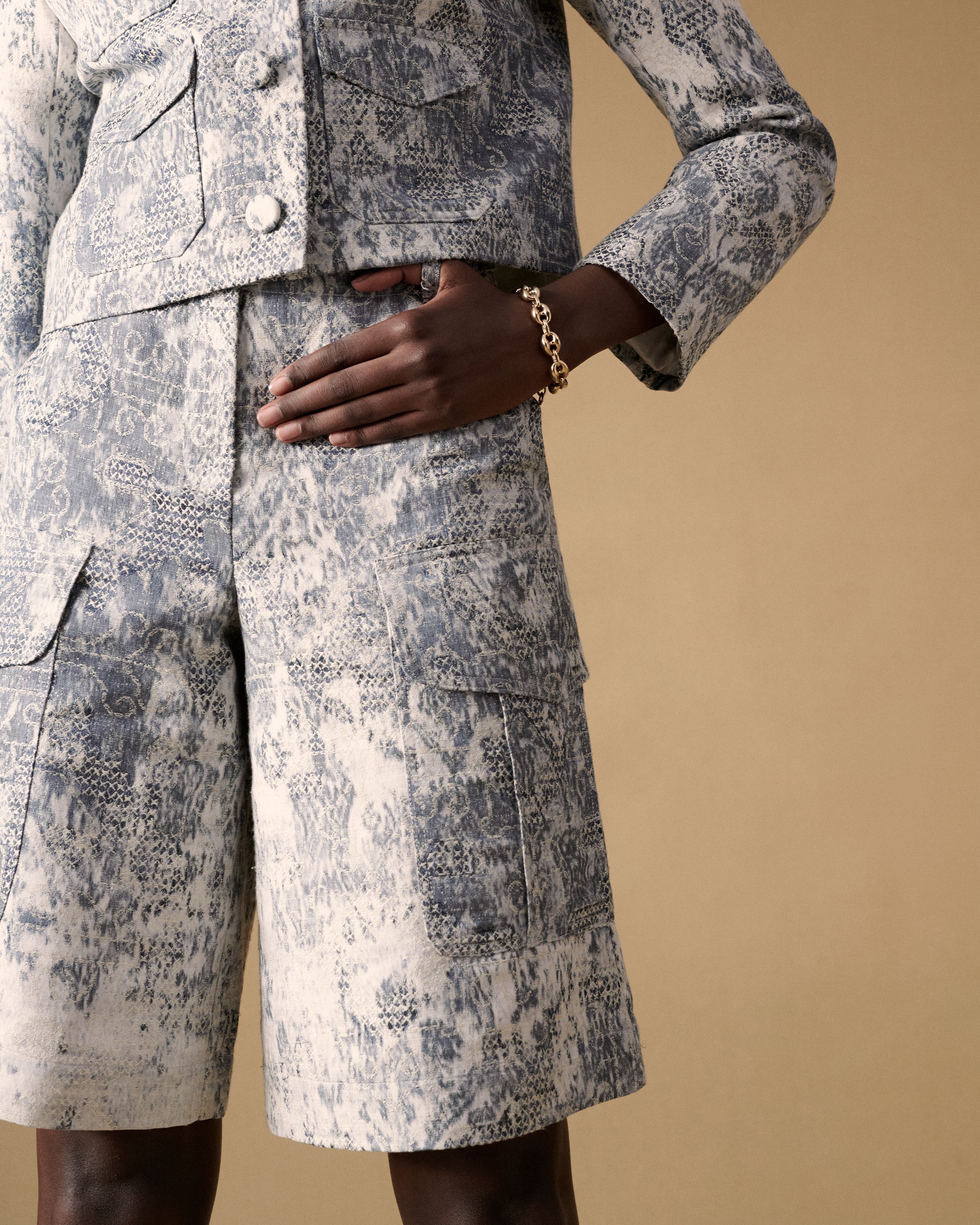 Close up of model's blue and white printed shorts with a gold chain bracelet